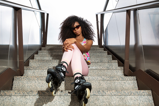 young black female skateboarder with sunglasses sitting on stairs looking at camera