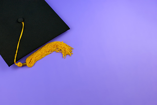 Vuelta al cole. Gorra de graduación negra sobre un fondo púrpura. Concepto de graduación. Tapa de la placa de mortero negro photo