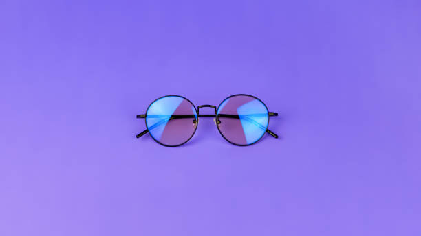 istock Glasses with a blue light filter to protect the eyes while working at the computer. Round glasses for filtering blue light. Stylish round glasses on a purple background, top view 1330609186
