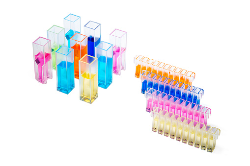 View from above on Different Quartz or polymer Cuvettes for photometric analysis in chemistry, medical research, biochemistry filled with liquids of different colors on white background, Copy space.