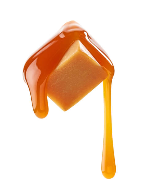 caramel sauce flowing on flying caramel candy caramel sauce flowing on flying caramel candy isolated on white background caramel stock pictures, royalty-free photos & images