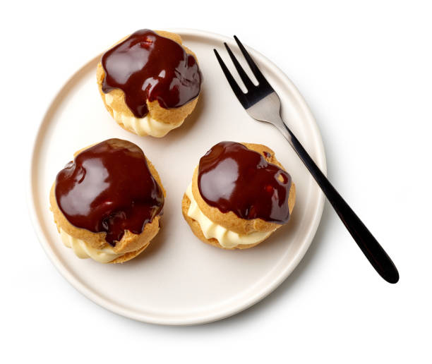 plate of freshly baked cream puffs plate of freshly baked cream puffs covered with melted chocolate isolated on white background, top view cream cake stock pictures, royalty-free photos & images