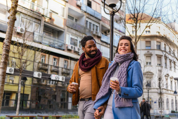 un hombre multiétnico y una mujer enamorada se divierten en el parque. - couple outdoors coffee friendship fotografías e imágenes de stock