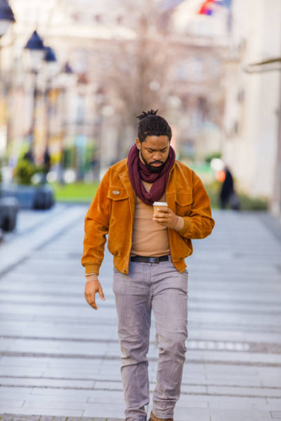 istock A Young African-American is Drinking Coffee and Walking Down the City District. 1330613372