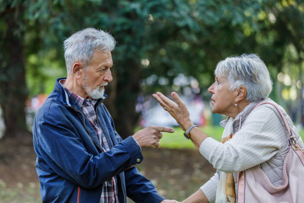ein älterer mann und seine frau führen eine ernsthafte diskussion in einem öffentlichen park. - couple senior adult sadness emotional stress stock-fotos und bilder