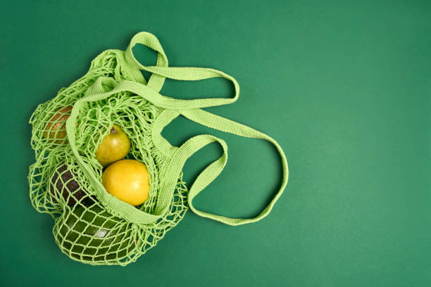 istock Green string eco shopping bag with vegatables avocado, lemon on green background 1330618351