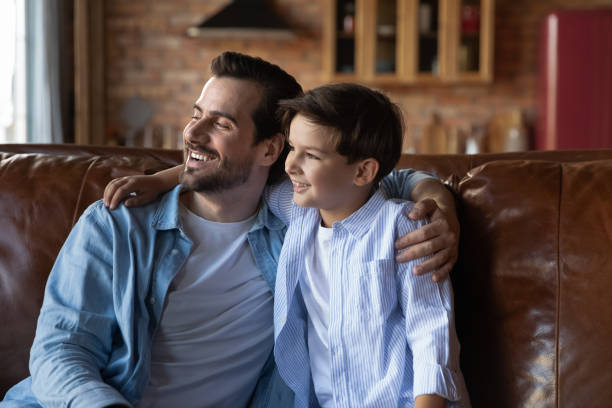 istock Happy preschooler son and daddy sitting together on sofa 1330622455