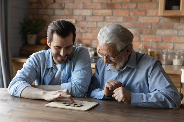 istock Grownup son and senior father engaged in logical board game 1330622470