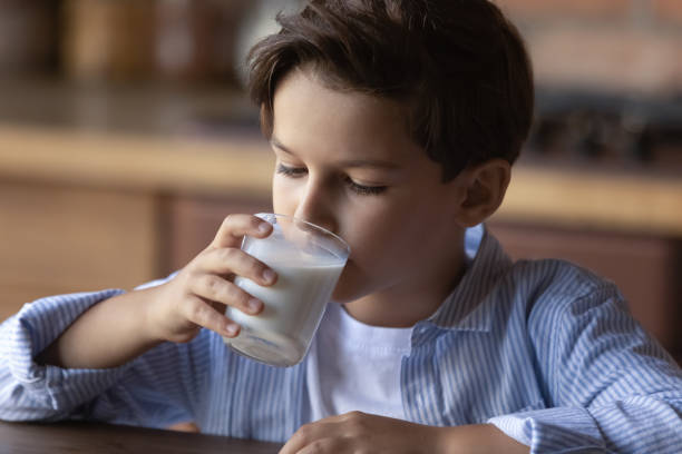istock Preschooler boy drinking milk from glass during breakfast in kitchen 1330622477