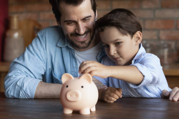 istock Happy dad teaching smart little son to save money 1330622480