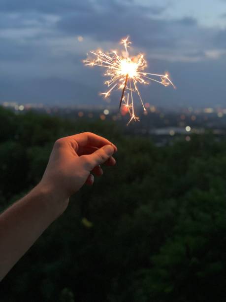 istock Man holding glittering sparkler at summer celebration 1330627120