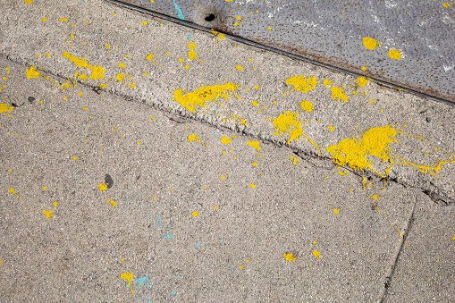 A view of yellow paint spattered on the ground.