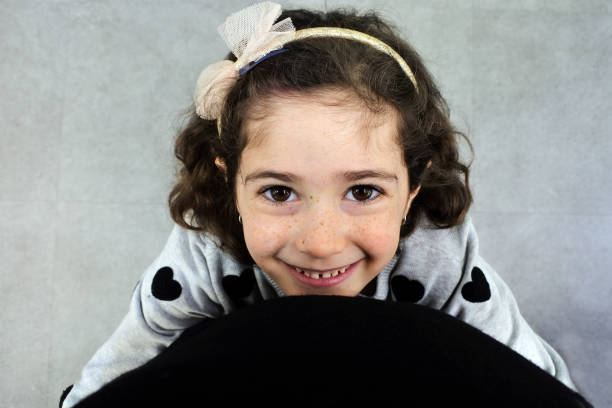 POV (point of view) of a father looking down at his young daughter (female age 7-8) happy smiling face looking up towards him and hugs him from love.