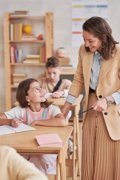 istock Female Teacher Helping Kids in School 1330639013