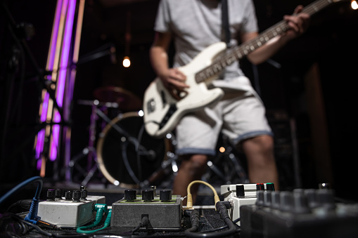 Bass guitar player on a stage with set of distortion effect pedals.