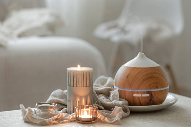 accogliente composizione domestica con umidificatore d'aria e candele su sfondo sfocato. - aromatherapy candles foto e immagini stock