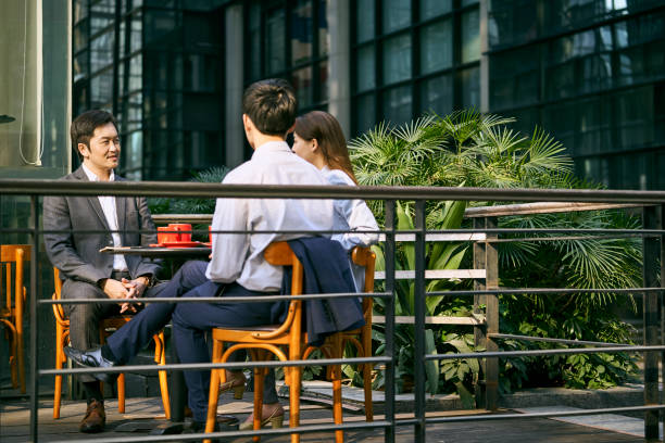 istock asian business colleagues chatting in sidewalk cafe 1330645585
