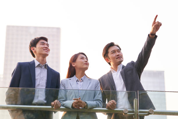 istock asian office workers standing on rooftop discussing business 1330645616