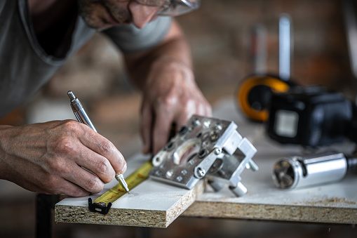 A carpenter in the process, a professional tool for precision drilling in wood.