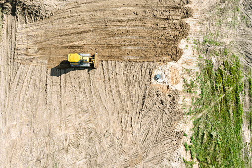 yellow bulldozer leveling the ground before construction works. aerial top view