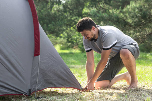 istock A man outdoors in the process of setting up a tent. 1330650401