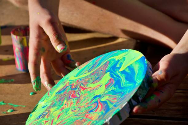 istock Close-Up of Boy's Hands Making a Marbled Effect Painting on Round Canvas 1330651108