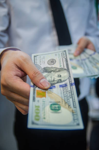 Man offering batch of hundred dollar bills. stock photo