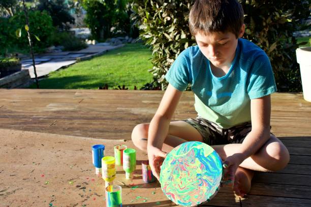 istock Boy Making a Marbled Effect Painting on Round Canvas 1330652055