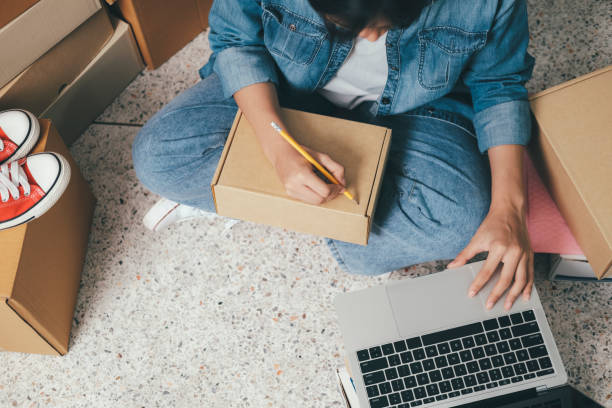 istock Online small business owner writing address on parcel box. 1330652226