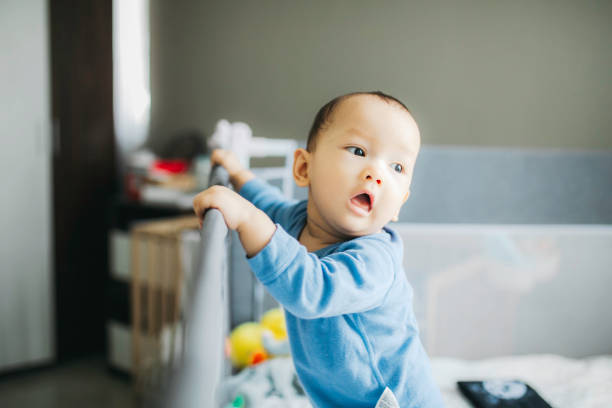 istock portrait asian baby standing and hold a bed frame 1330653026