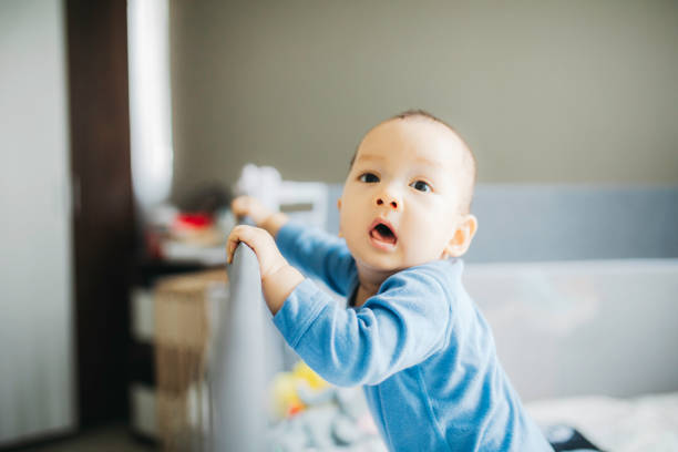 istock portrait asian baby standing and hold a bed frame 1330653046