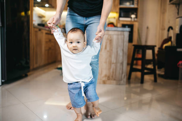 istock baby holding hands with young adult taking first steps learning 1330653161