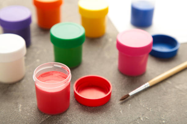 istock Multicolored jars of gouache and a brush on a grey table. Creative kit. 1330653238