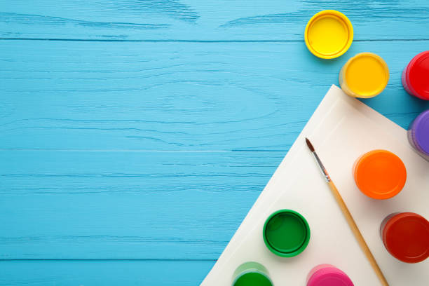 istock Multicolored jars of gouache and a brush on a blue background. Creative kit. 1330653603