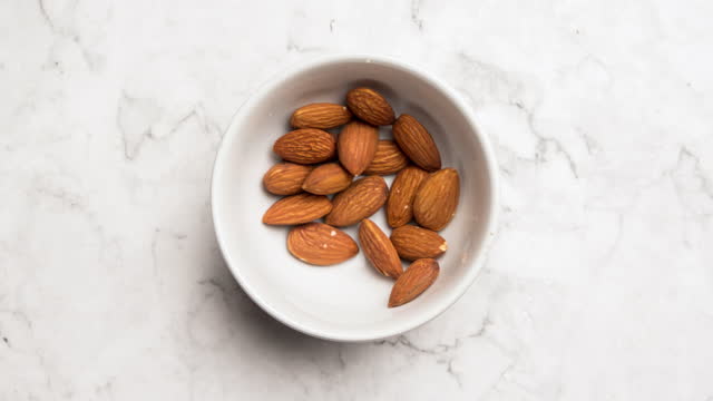 Top view Stop motion animation Almonds nuts in a white bowl.