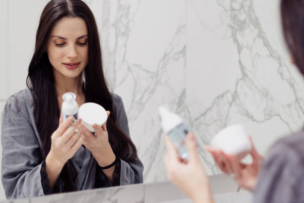 kobieta z produktami kosmetycznymi w łazience w domu - cosmetics moisturizer bottle beauty zdjęcia i obrazy z banku zdjęć