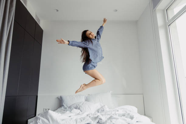 istock Happy woman jumping on bed in morning 1330655879