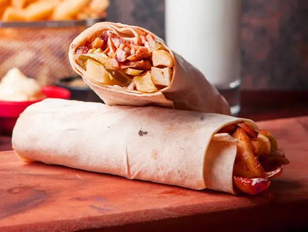 Side view shawarma with fried potatoes and ayran and mayonnaise in board cookware on stone background