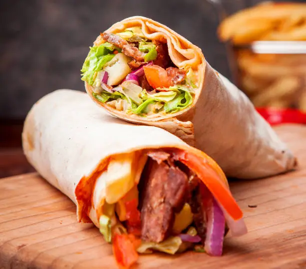 Side view shawarma with fried potatoes in board cookware on stone background