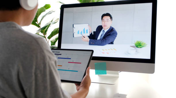 istock Video conference, Work from home, Asian man making video call to business team with virtual web while holding digital tablet, Contacting colleague by conference on laptop computer at home 1330659960