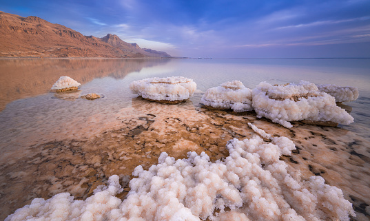 Beautiful Israeli landscape of the Dead Sea, the lowest place on Earth: salt formations and clouds with Judean Desert mountain in the background