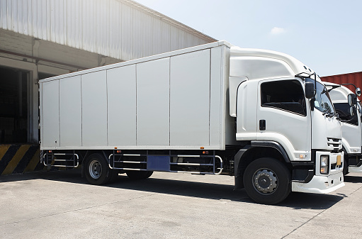 Cargo Trucks Parked Loading at Dock Warehouse. Cargo Shipment. Industry Freight Truck Transportat. Shipping Warehouse Logistics.