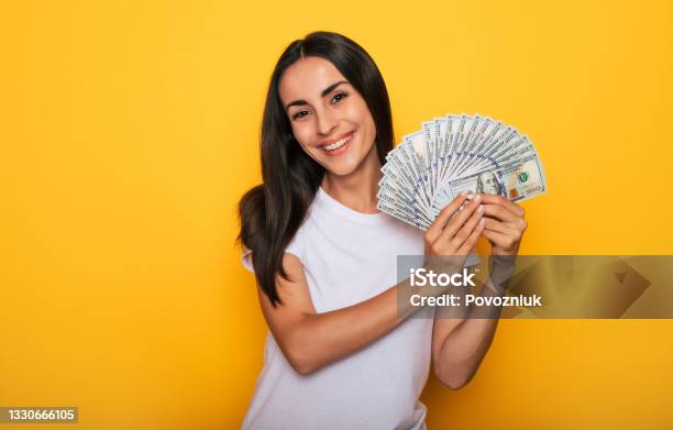 Young Happy Excited Beautiful Woman Emotionally Looking In The Camera With A Lot Of Money In Her Hands And Having Fun Isolated On Yellow Background Stock Photo - Download Image Now