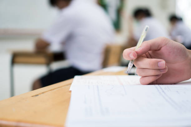 istock Hand female Asian students taking exam test and concentration reading document exercise at classroom in high school. Teenager notes for SAT PISA measurement educational, back to school for evaluation 1330666756