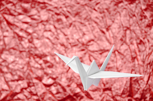 Red paper dove origami isolated on a blank grey background.