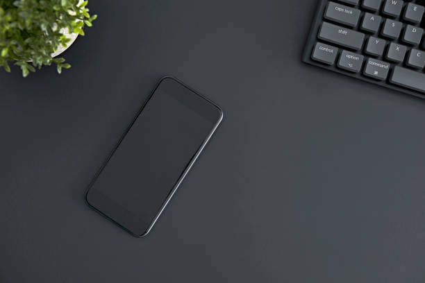 Top down view of mobile phone with black blank screen laying on desk. Modern technology, wireless device and transfer of energy concept.