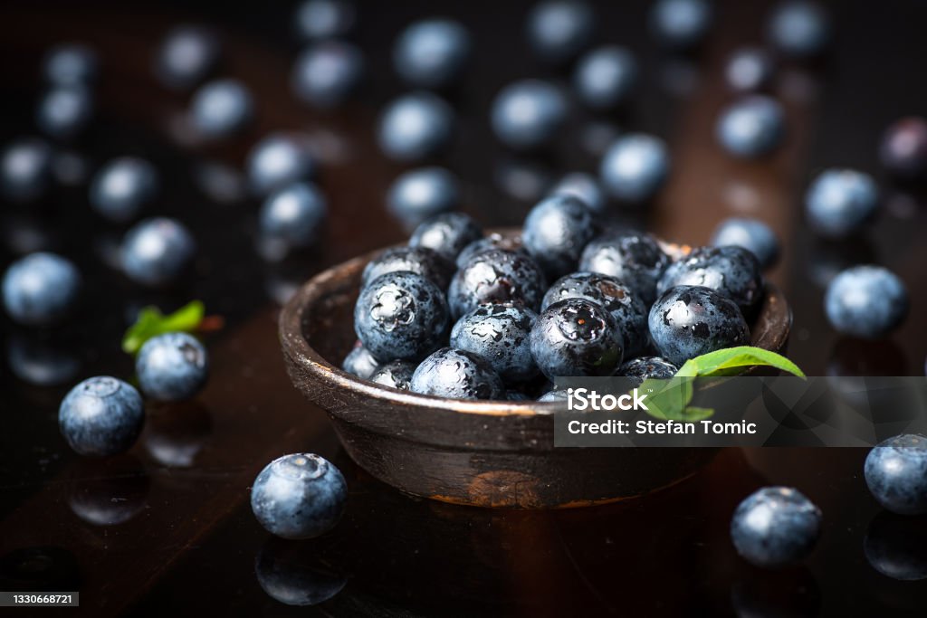 Fresh blueberry fruit in a bowl on dark background Fresh organic blueberry fruit in a bowl on dark background closeup macro Bilberry - Fruit Stock Photo