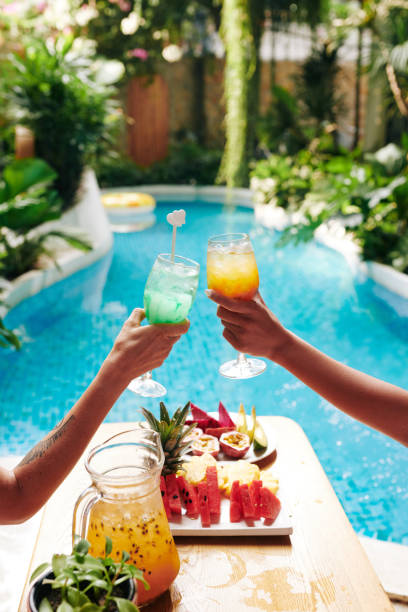 amigos clinking vasos de cócteles - al lado de la piscina fotografías e imágenes de stock