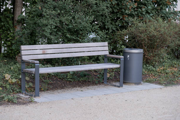 istock an abandoned park bench next to a walkway, next to it is a metal trash can. 1330670257