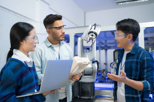 istock Caucasian male engineer standing hold a robot controller next to Asian female apprentice holding laptop 1330673162